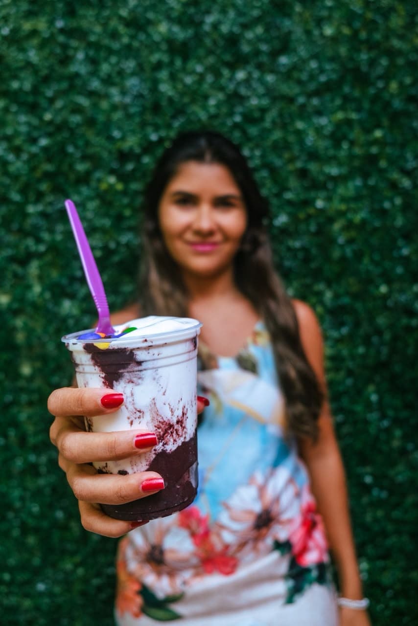 Cliente sorrindo com um copo de açaí da Açaí Tropical